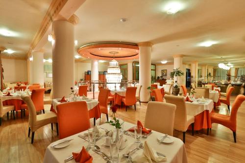 a restaurant with white tables and orange chairs at Harmony Hotel in Addis Ababa