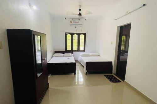 1 dormitorio con 2 camas en una habitación en KARIYIL KAYALORAM HOMESTAY, en Shertallai