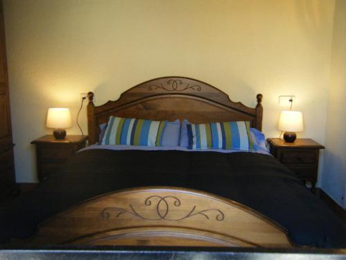 a bedroom with a wooden bed with two lamps at Fonda Ca l'Abel in Lles