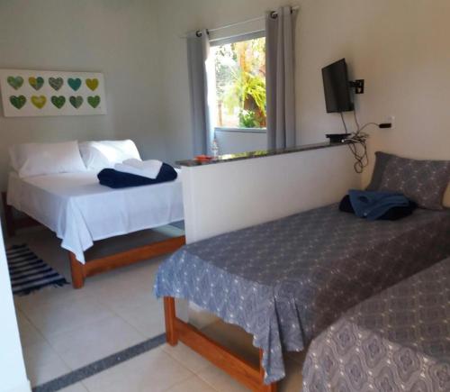 a hotel room with two beds and a television at Pousada Chalés dos Montes in Santana dos Montes