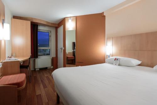 Cette chambre comprend un grand lit et un bureau. dans l'établissement ibis Clermont Ferrand Sud Herbet, à Clermont-Ferrand