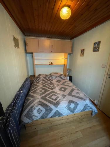 a bed in a small room with a wooden ceiling at Le chalet de Virginie in Resteigne