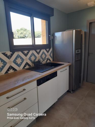 Il comprend une cuisine équipée d'un réfrigérateur en acier inoxydable et une fenêtre. dans l'établissement la cachette, à Vitrac-sur-Montane