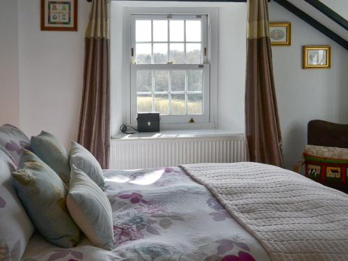 sypialnia z dużym łóżkiem i oknem w obiekcie Trekeive Cottage w mieście Saint Cleer
