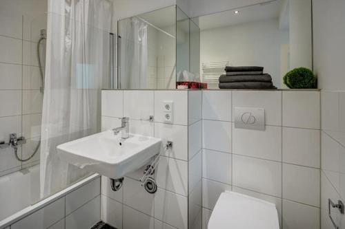 ein Badezimmer mit einem Waschbecken, einem WC und einem Spiegel in der Unterkunft Cozy modern apartment with garden in the center next to Oktoberfest in München