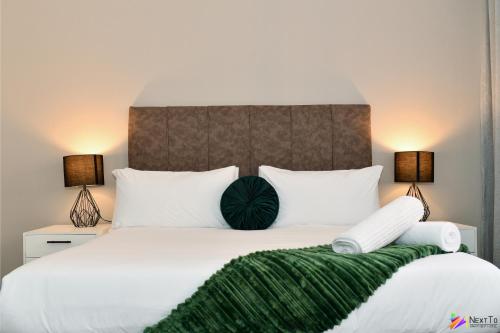 a bedroom with a large white bed with two lamps at Next To Apartment Hotel in Pretoria