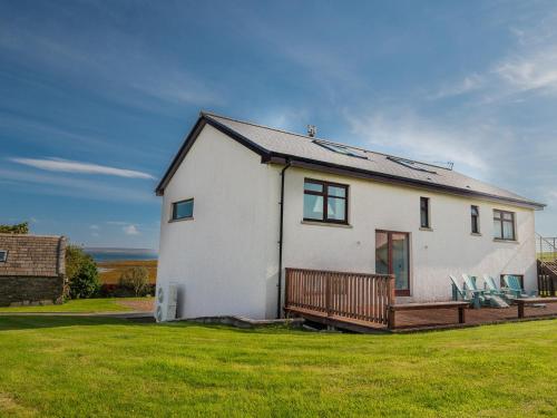 a white house with a wooden deck on a lawn at The Steading in Stromness