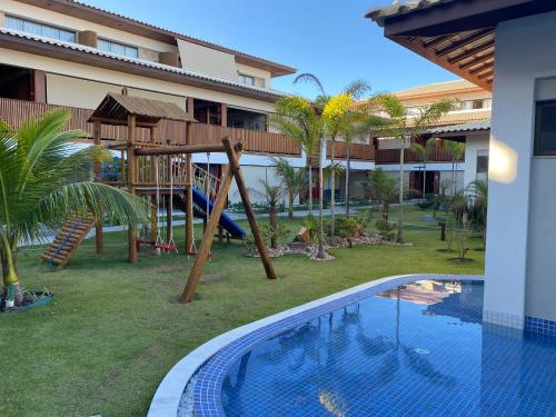a resort with a playground next to a swimming pool at Itacimirim - Duplex Aconchegante, Pé na Areia in Itacimirim