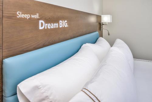 a bed in a hotel room with a sign that readssleep well dream big at EVEN Hotel Eugene by IHG in Eugene