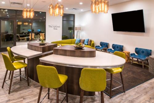 a waiting room with yellow chairs and tables and a flat screen tv at EVEN Hotel Eugene by IHG in Eugene