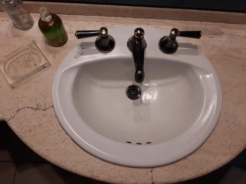 a white sink with two faucets on a counter at Cuartos en el segundo piso de casa de artista en Flores in Buenos Aires