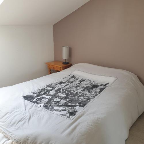 Una cama con una manta blanca y negra. en les chambres de Mélis, en Crémieu