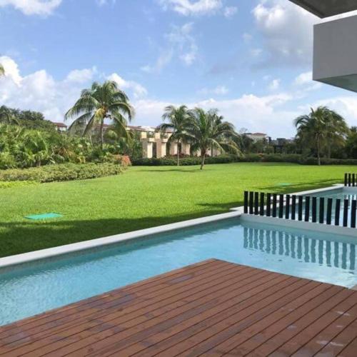 a swimming pool in front of a yard with palm trees at Condo/ Depa - Marea Azul - Playa del Carmen in Playa del Carmen