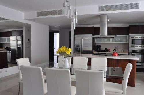a kitchen with a dining table and white chairs at Condo/ Depa - Marea Azul - Playa del Carmen in Playa del Carmen