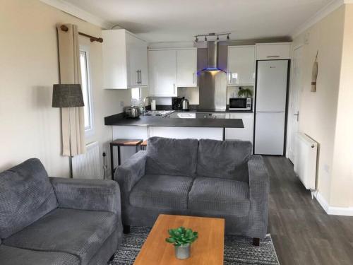 a living room with a couch and a table and a kitchen at Marios Lodge in Padstow