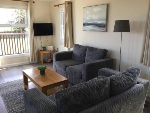 a living room with two couches and a table at Marios Lodge in Padstow