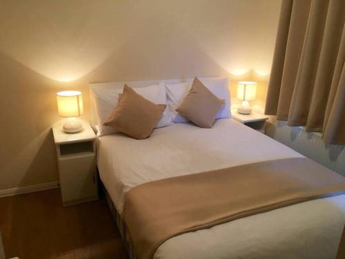 1 dormitorio con 1 cama blanca grande y 2 lámparas en Marios Lodge, en Padstow