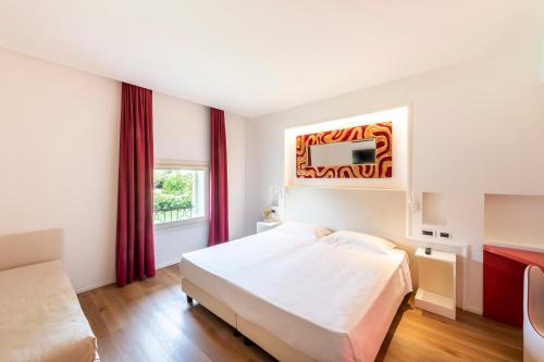 a hotel room with a bed and a tv at Hotel Villa I Pini in Malo