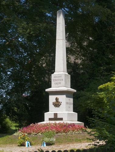 a monument with flowers in front of a tower at FeWo HoLiDay ApartMENT Allgäu in Ottobeuren