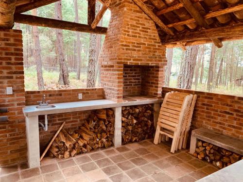 a fireplace in a brick room with a table and a chair at Cabañas Zacatlan Zacapa in San José Ayotla