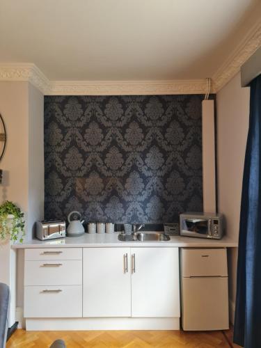 a kitchen with white cabinets and a black wall at Rainworth Lodge in Nottingham