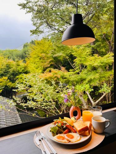 a plate of breakfast food on a table with a window at Yufuin Hoshinosato in Yufuin