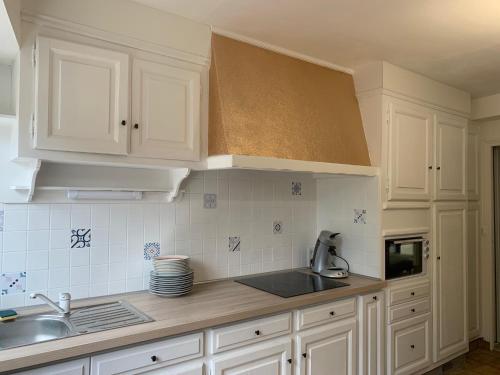 une cuisine avec des armoires blanches et un évier dans l'établissement Appartement RDC 9 personnes, 2 chambres, wifi, proche du centre, à La Bourboule