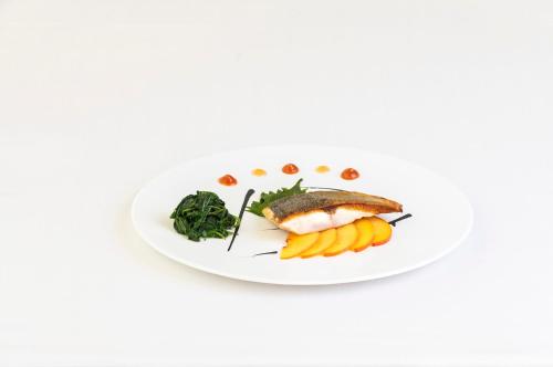 a plate of food with fish and vegetables on it at Hotel Villa I Pini in Malo