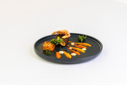 a black plate of food with carrots and meat at Hotel Villa I Pini in Malo