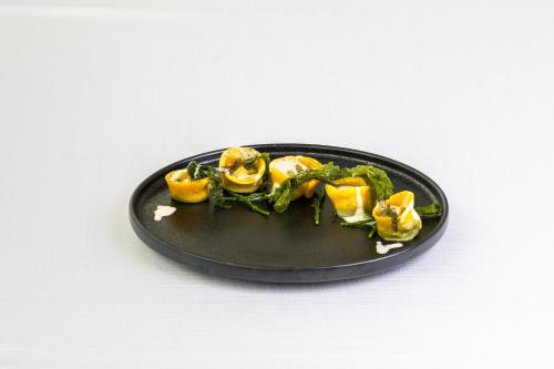 a black plate with food on a white table at Hotel Villa I Pini in Malo