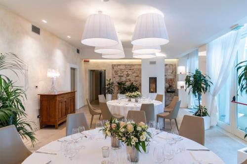a large dining room with white tables and chairs at Hotel Villa I Pini in Malo