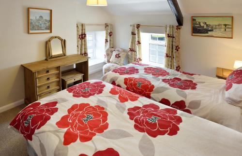 a bedroom with two beds with red and white blankets at Cronk Darragh Cottage in Castletown