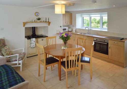 a kitchen with a wooden table and chairs and a kitchen with a sink at Cronk Darragh Cottage in Castletown