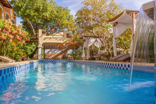 uma piscina exterior com um guarda-sol e uma piscina em Hotel Villa Terra Viva em Jericoacoara