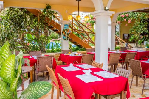a restaurant with red tables and chairs and plants at Hotel Villa Terra Viva in Jericoacoara