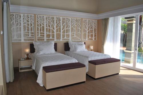 a bedroom with two beds with white sheets and a window at Kori Maharani Villas - Lagoon Pool Access 3 in Siyut