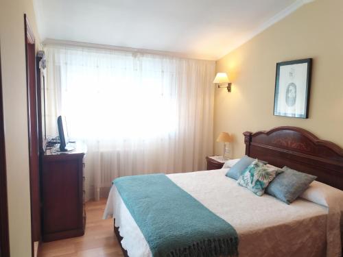sypialnia z łóżkiem z niebieskimi poduszkami i oknem w obiekcie Piso Avenida Castelao XXL w mieście Isla de Arosa