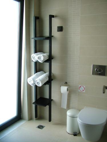 a bathroom with a toilet and a shelf with towels at Sugar and Almond in Agios Stefanos