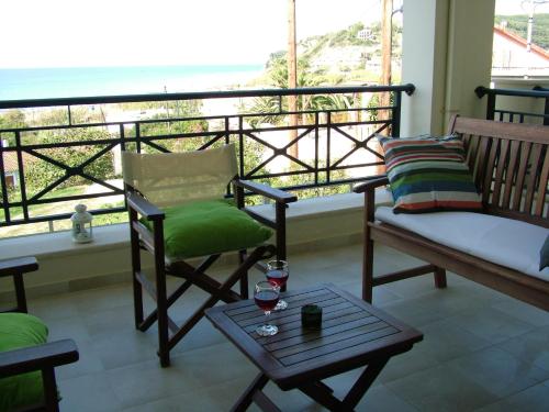 a balcony with chairs and a table and a window at Sugar and Almond in Agios Stefanos
