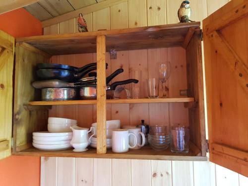 a wooden cabinet with cups and dishes on it at Eco Accommodation Cornflower in Craven Arms