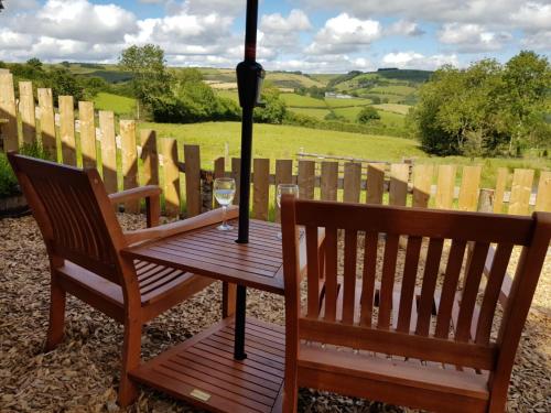 two chairs and a table with a glass of wine at Eco Accommodation Cornflower in Craven Arms