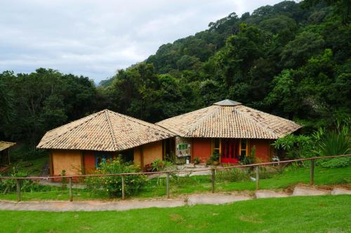 zwei Häuser mit Strohdächern auf einem Feld in der Unterkunft Pousada Spa Saúde Melhor in Extrema