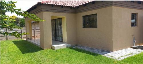 a small house with a green lawn in front of it at The glory house in Alberton
