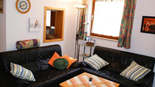 a living room with a black leather couch with pillows at Apartment Famli Relax Kärnten in Feistritz im Rosental