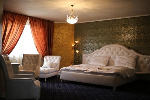 a bedroom with a bed and a chair and a chandelier at Hotel Kotva in Bratislava