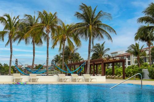 una piscina en el complejo con palmeras y un tobogán en Condo/ Depa - Marea Azul - Playa del Carmen en Playa del Carmen