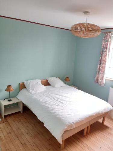a bedroom with a white bed and a chandelier at Maison de vacances-La balade des deux Caps in Audinghen