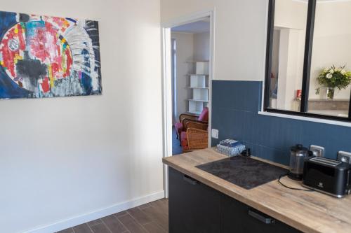 a kitchen with a sink and a painting on the wall at Maison de vacances-La balade des deux Caps in Audinghen