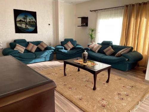 a living room with blue couches and a coffee table at Awesome Villa on a hill Families only in Cairo