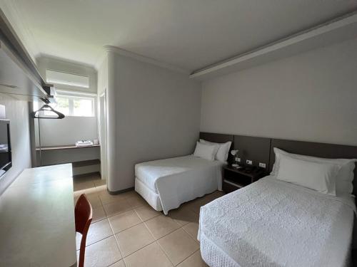 a hotel room with two beds and a table at Guaicurus Hotel in Chapadão do Sul